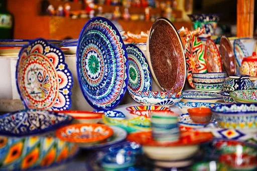 Turquoise-glazed bowls and plates drying on wooden racks in a Rishtan pottery workshop.