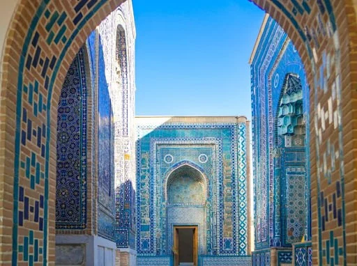 The narrow tiled corridor of the Shah-i-Zinda necropolis in Samarkand, lined with mausoleum portals.